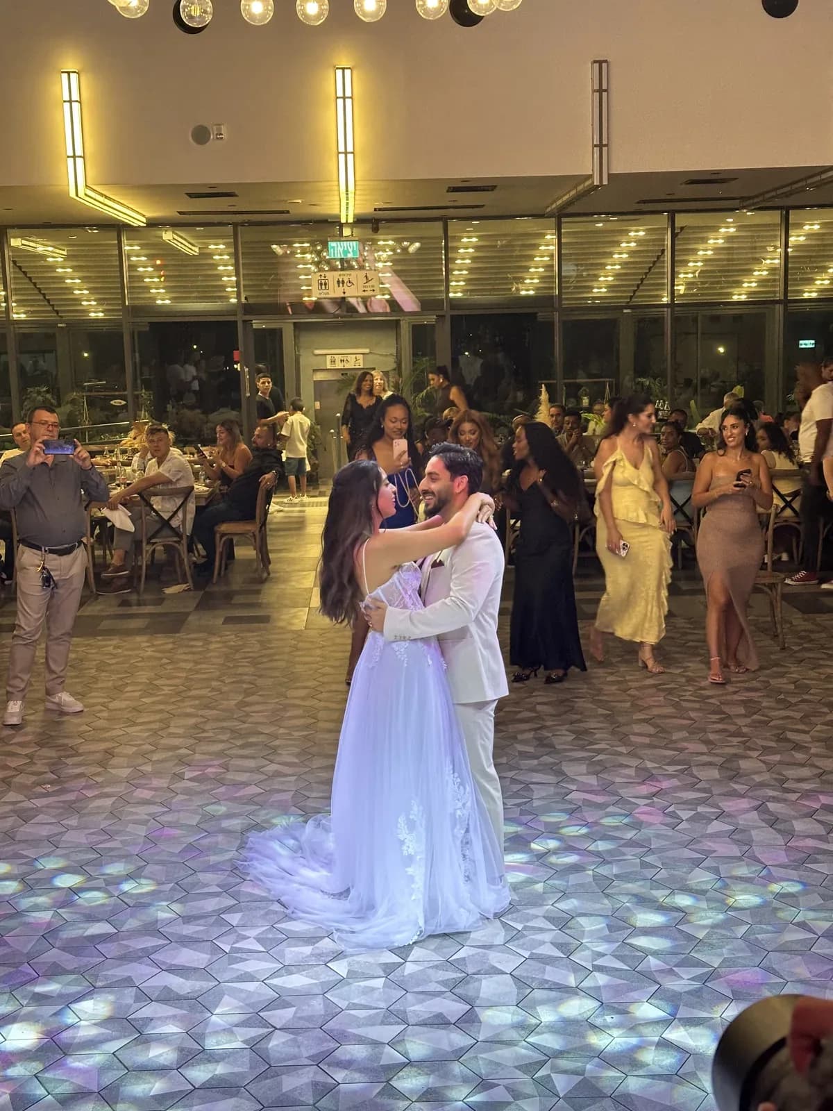 Bride and groom in their first dance with guests gathering around